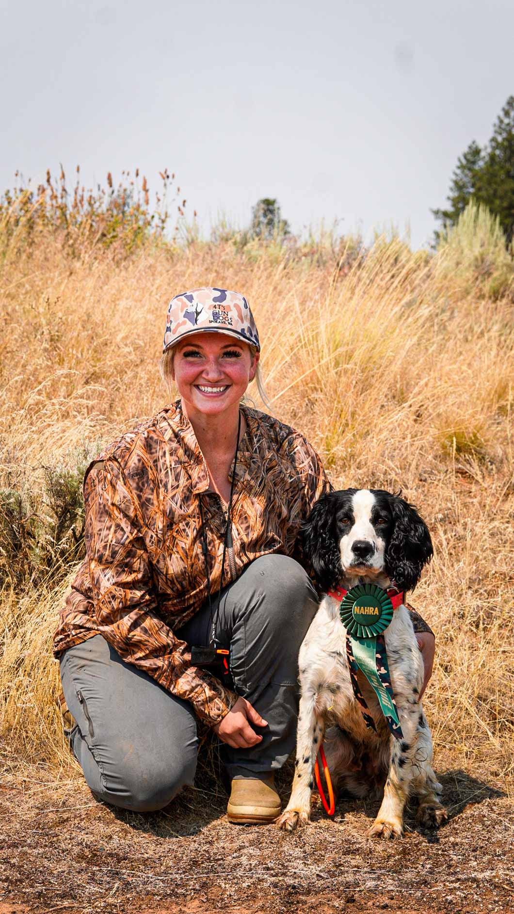 April kneeling with a hunting dog wearing an award ribbon in the field